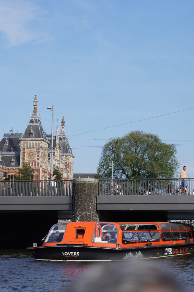 A boat traveling down a river next to a bridge Amsterdam 